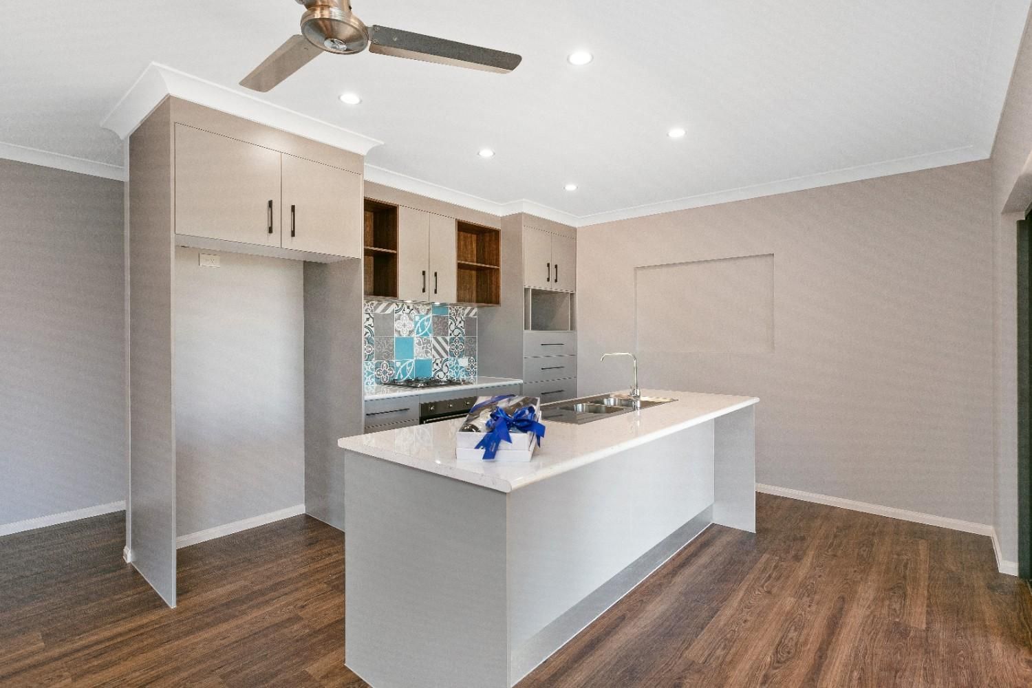 A Kitchen With a Large Island and a Ceiling Fan — Ashlee Jones Homes in Gordonvale, QLD