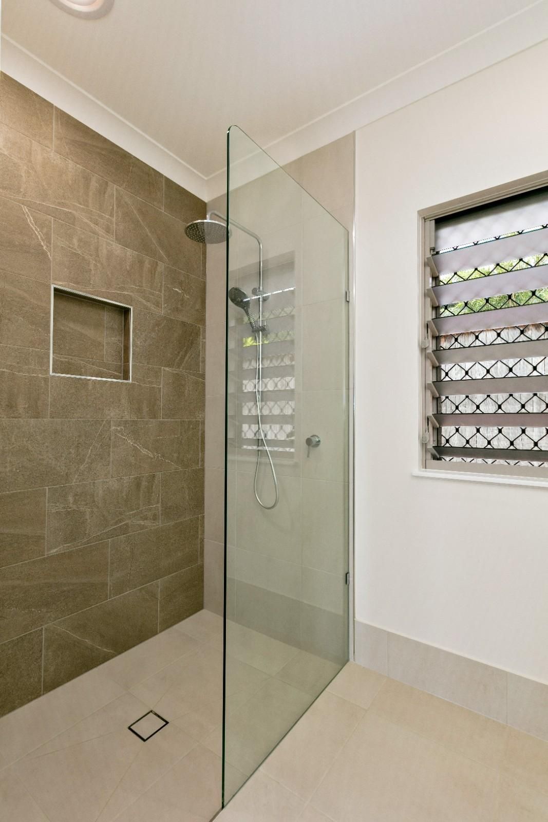 A Bathroom With a Walk in Shower and a Window — Ashlee Jones Homes in Gordonvale, QLD