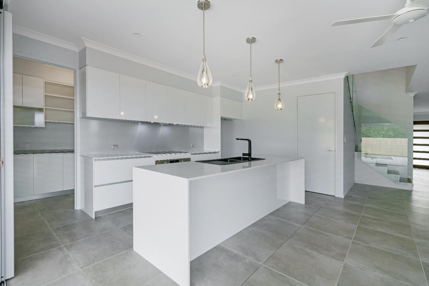 A Kitchen With White Cabinets and a Large Island in the Middle — Ashlee Jones Homes in Gordonvale, QLD