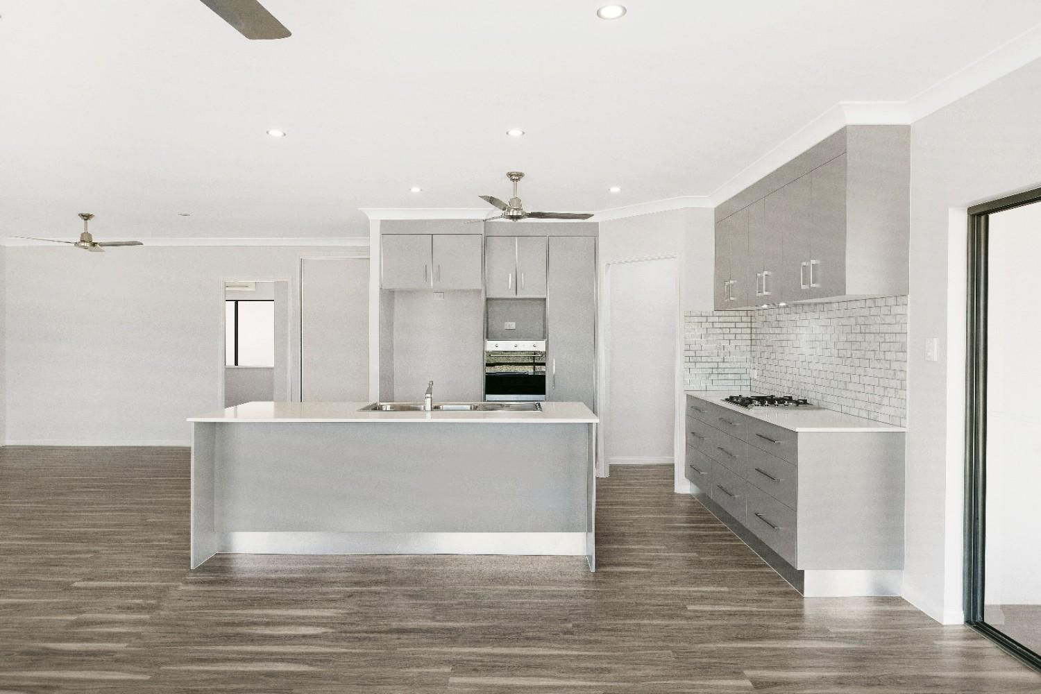 A Kitchen With a Large Island and a Ceiling Fan — Ashlee Jones Homes in Gordonvale, QLD
