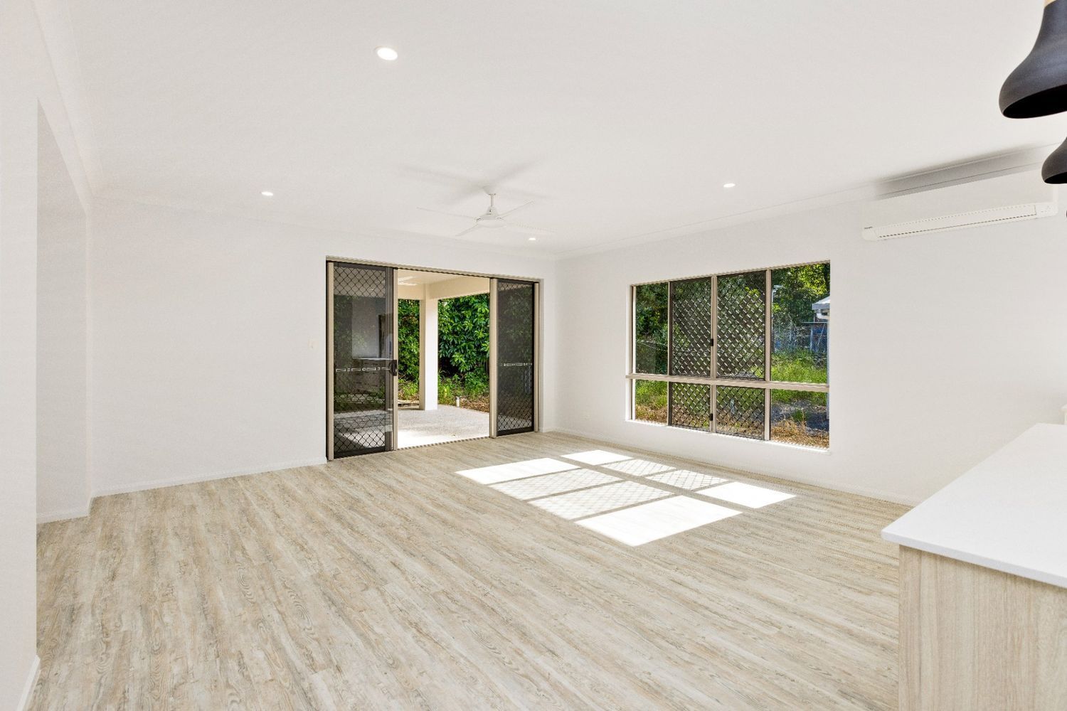 An Empty Living Room With Hardwood Floors and White Walls — Ashlee Jones Homes in Gordonvale, QLD