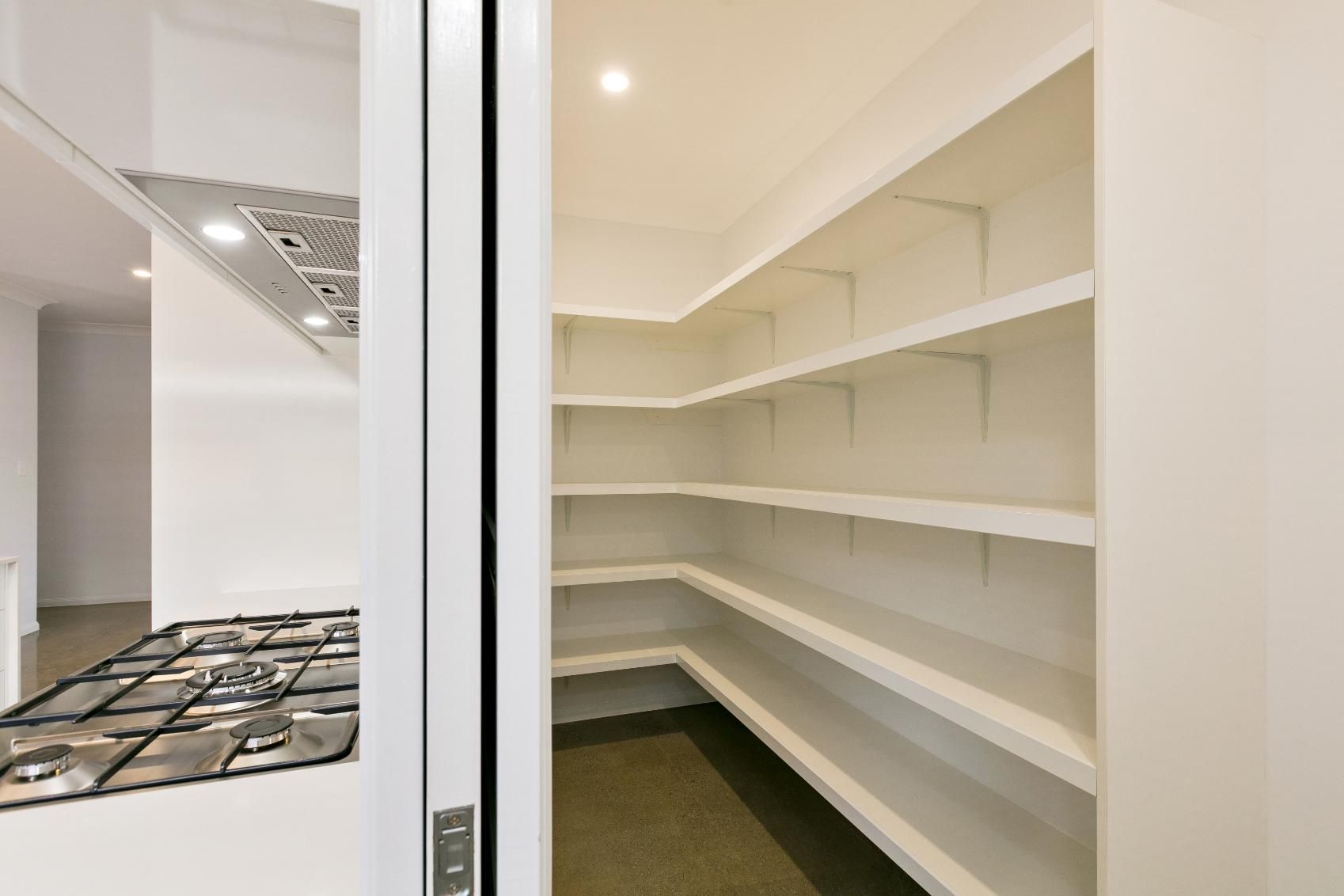 A Kitchen With a Stove and a Pantry With Shelves — Ashlee Jones Homes in Gordonvale, QLD