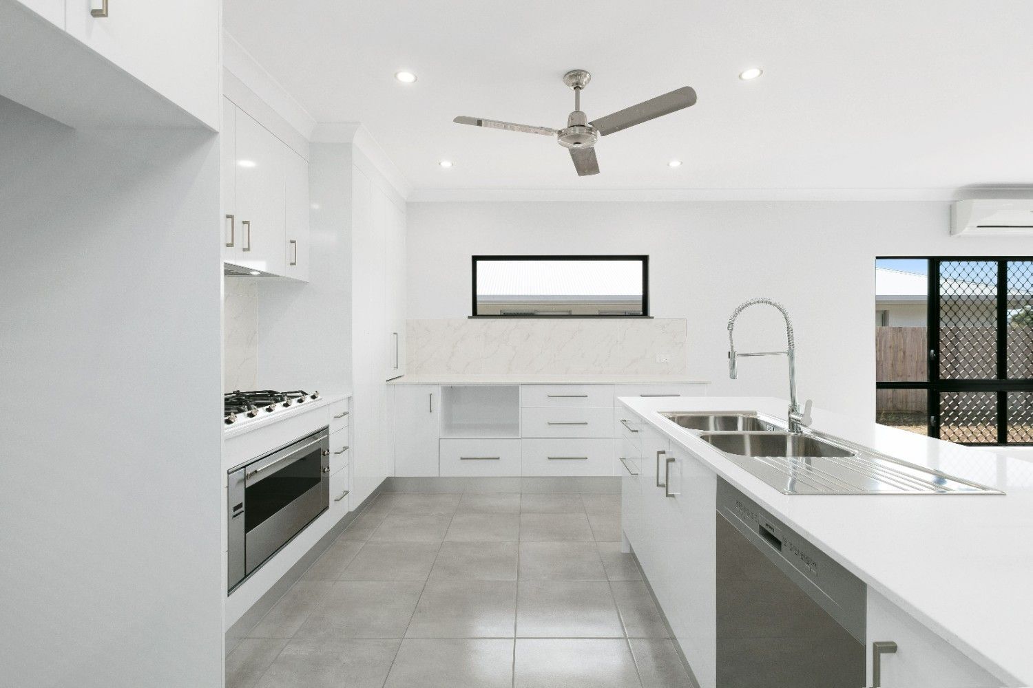 A Kitchen With White Cabinets and a Ceiling Fan — Ashlee Jones Homes in Gordonvale, QLD