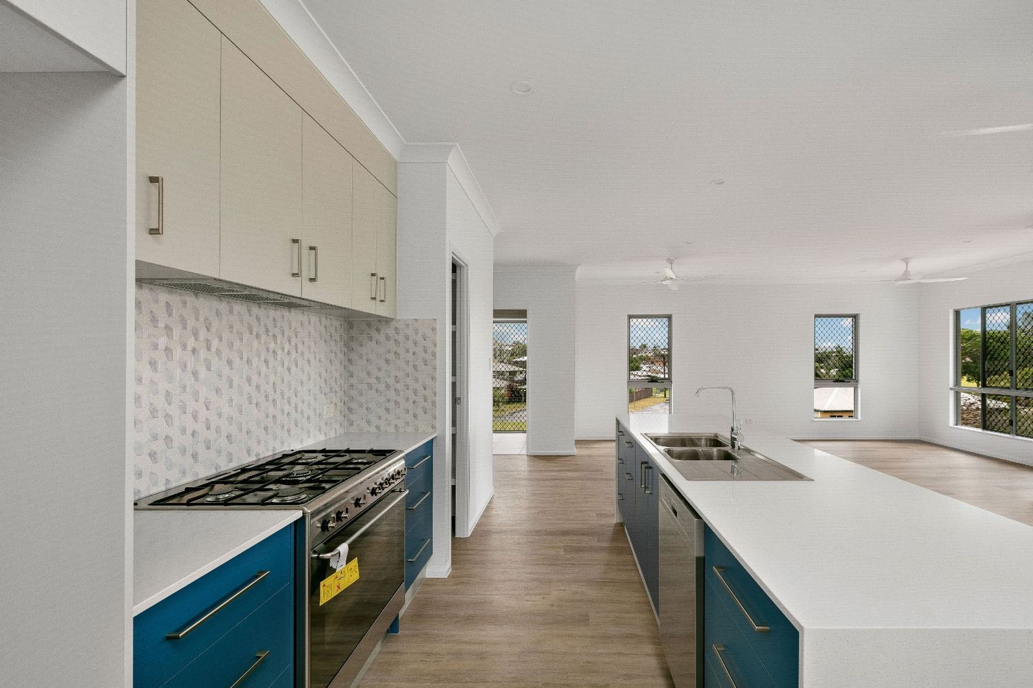 A Kitchen With Blue Cabinets, White Counter Tops, a Stove and a Sink — Ashlee Jones Homes in Gordonvale, QLD