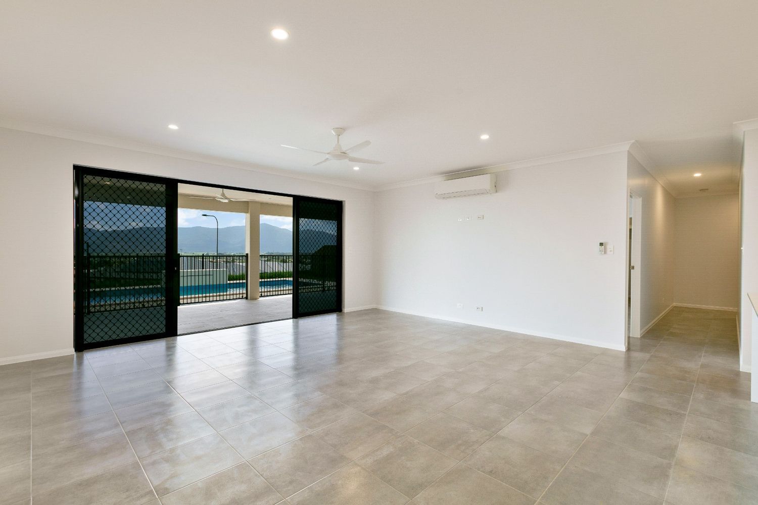 An Empty Living Room With Sliding Glass Doors and a Ceiling Fan — Ashlee Jones Homes in Gordonvale, QLD