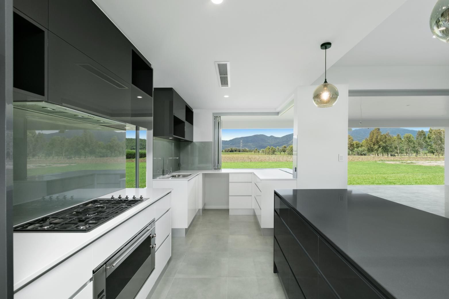 A Kitchen With a Stove Top Oven and a Large Island — Ashlee Jones Homes in Gordonvale, QLD