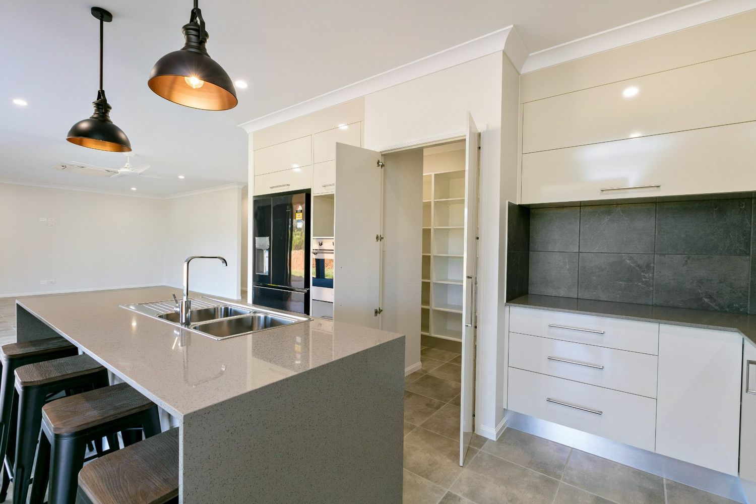 A Kitchen With a Large Island, Sink, and Stools — Ashlee Jones Homes in Gordonvale, QLD