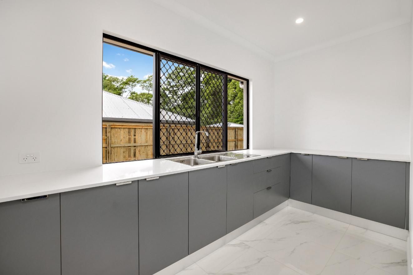An Empty Kitchen With a Large Window and a Sink — Ashlee Jones Homes in Gordonvale, QLD