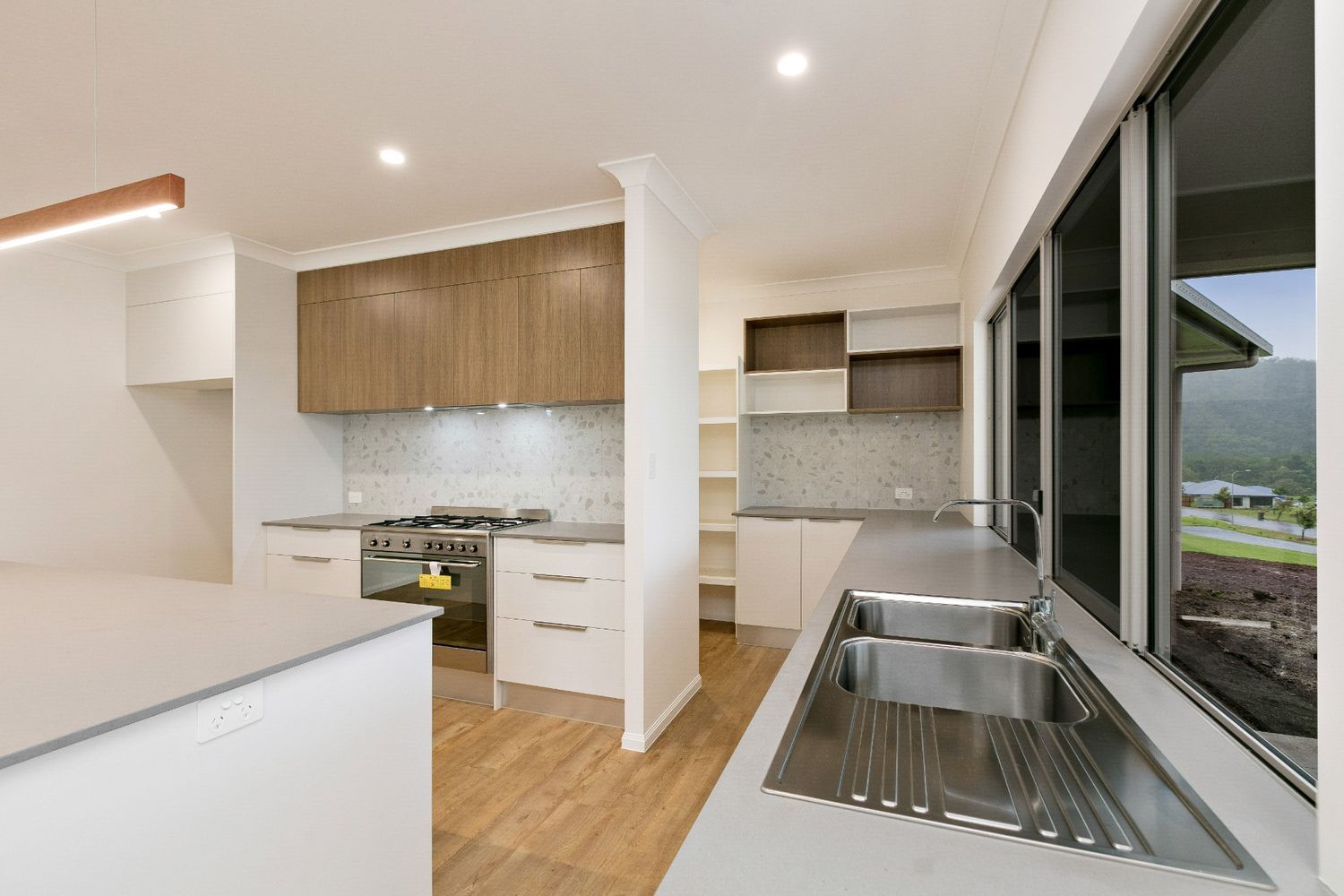 A Kitchen With a Sink, Stove, Cabinets and a Window — Ashlee Jones Homes in Gordonvale, QLD