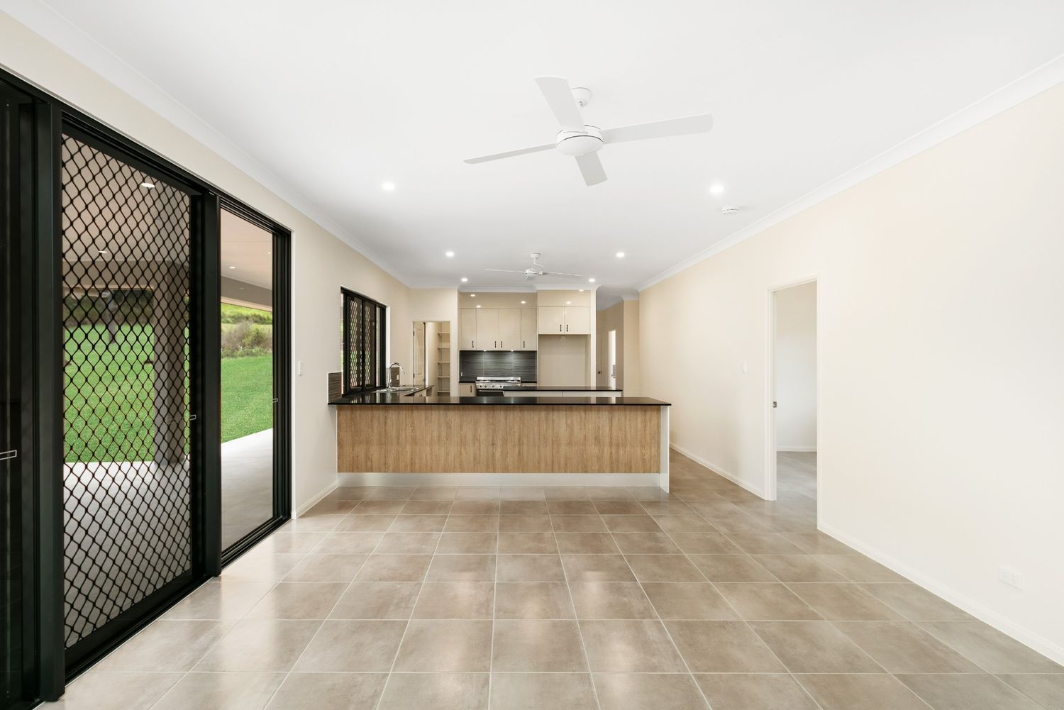 An Empty Room With a Kitchen and a Ceiling Fan — Ashlee Jones Homes in Gordonvale, QLD