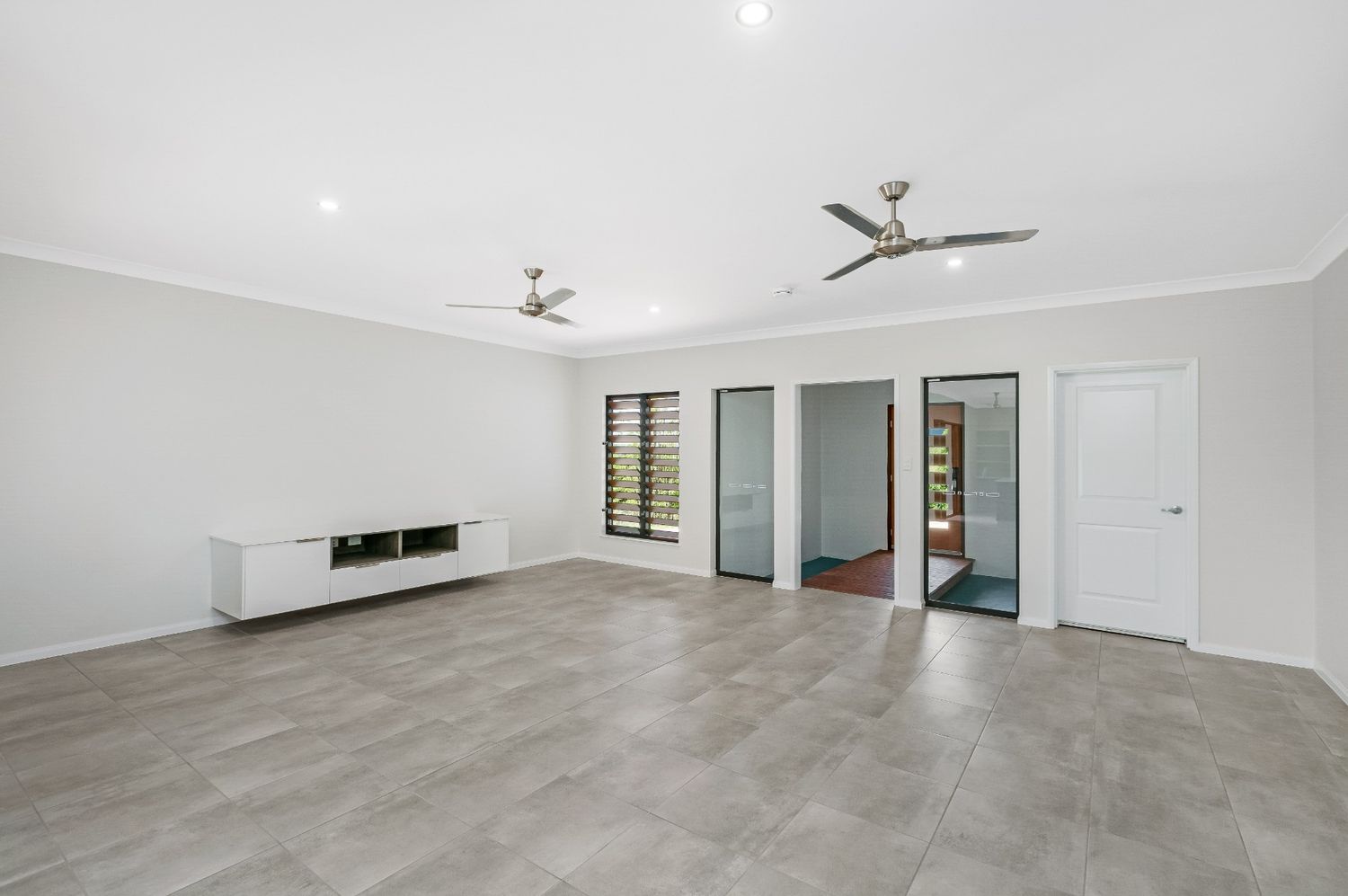 An Empty Living Room With a Ceiling Fan and a Television Stand — Ashlee Jones Homes in Gordonvale, QLD