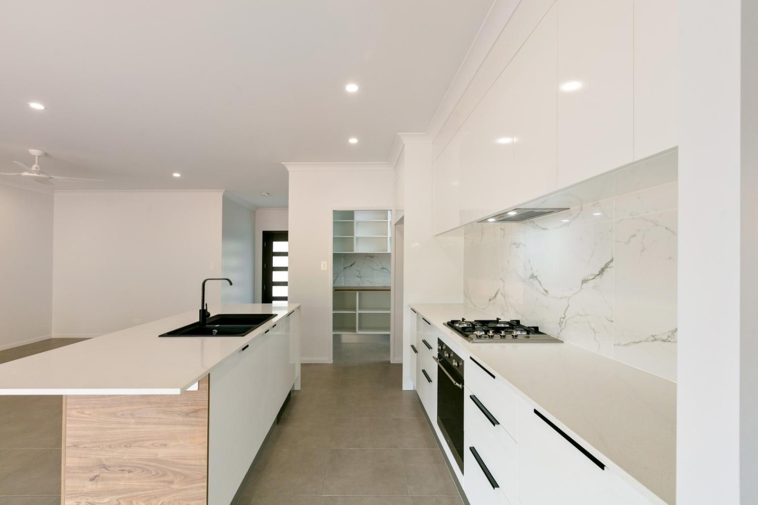 A Kitchen With White Cabinets and a Wooden Island — Ashlee Jones Homes in Gordonvale, QLD