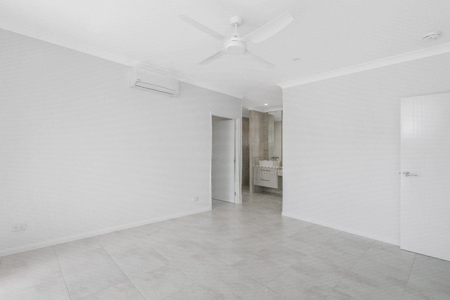 An Empty Room With a Ceiling Fan and a Bathroom in the Background — Ashlee Jones Homes in Gordonvale, QLD