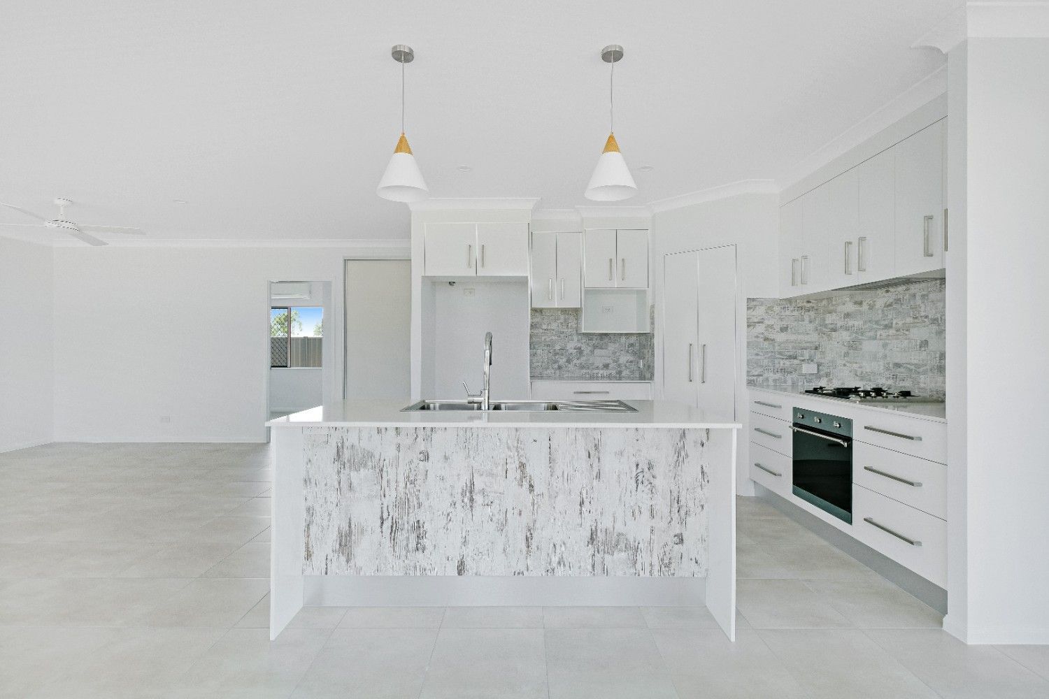 An Empty Kitchen With White Cabinets and a Large Island — Ashlee Jones Homes in Gordonvale, QLD