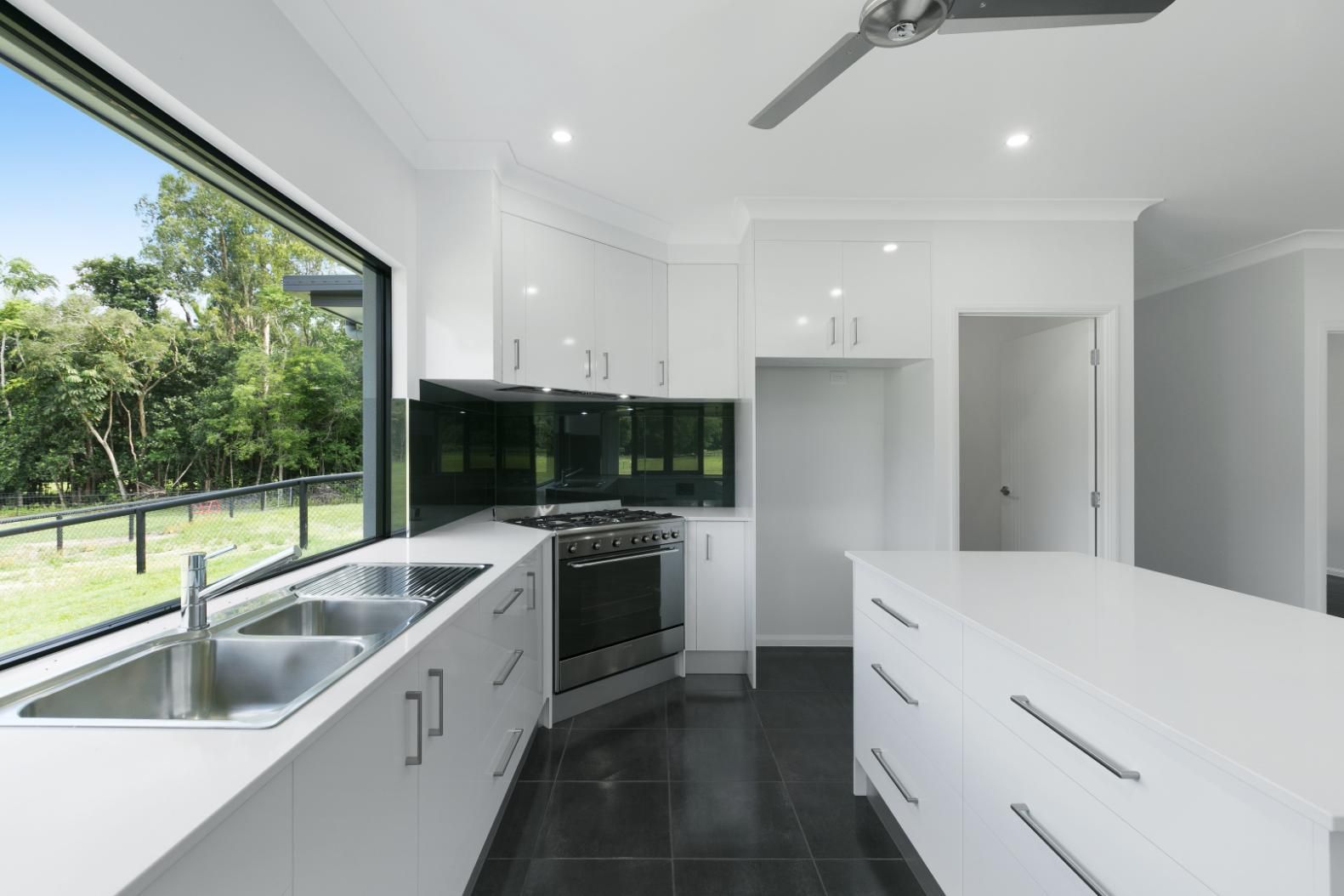 A Kitchen With White Cabinets and a Ceiling Fan — Ashlee Jones Homes in Gordonvale, QLD