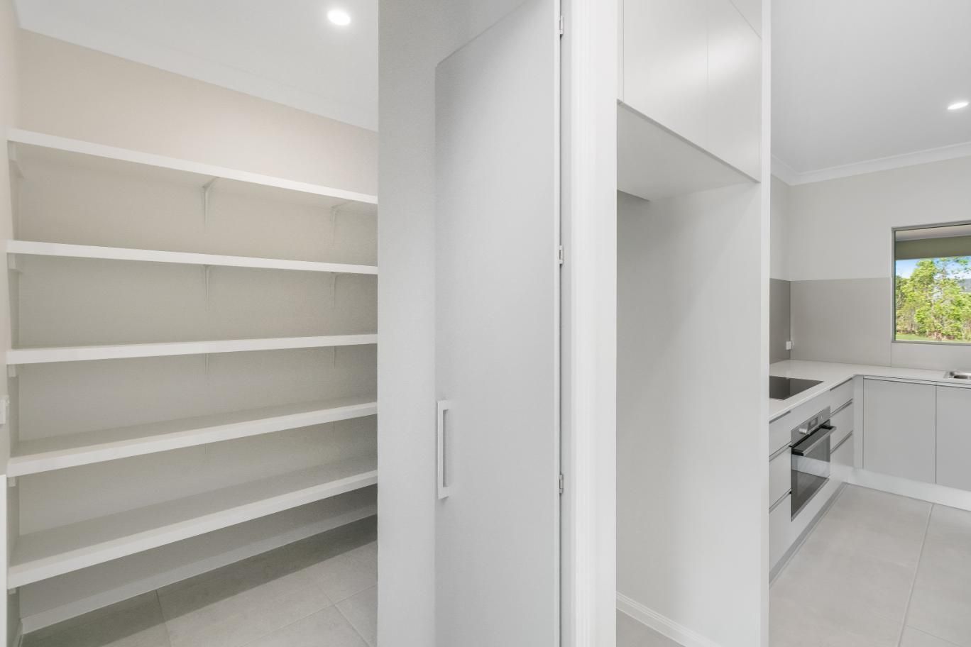 A Kitchen With White Cabinets and Shelves and a Pantry — Ashlee Jones Homes in Gordonvale, QLD