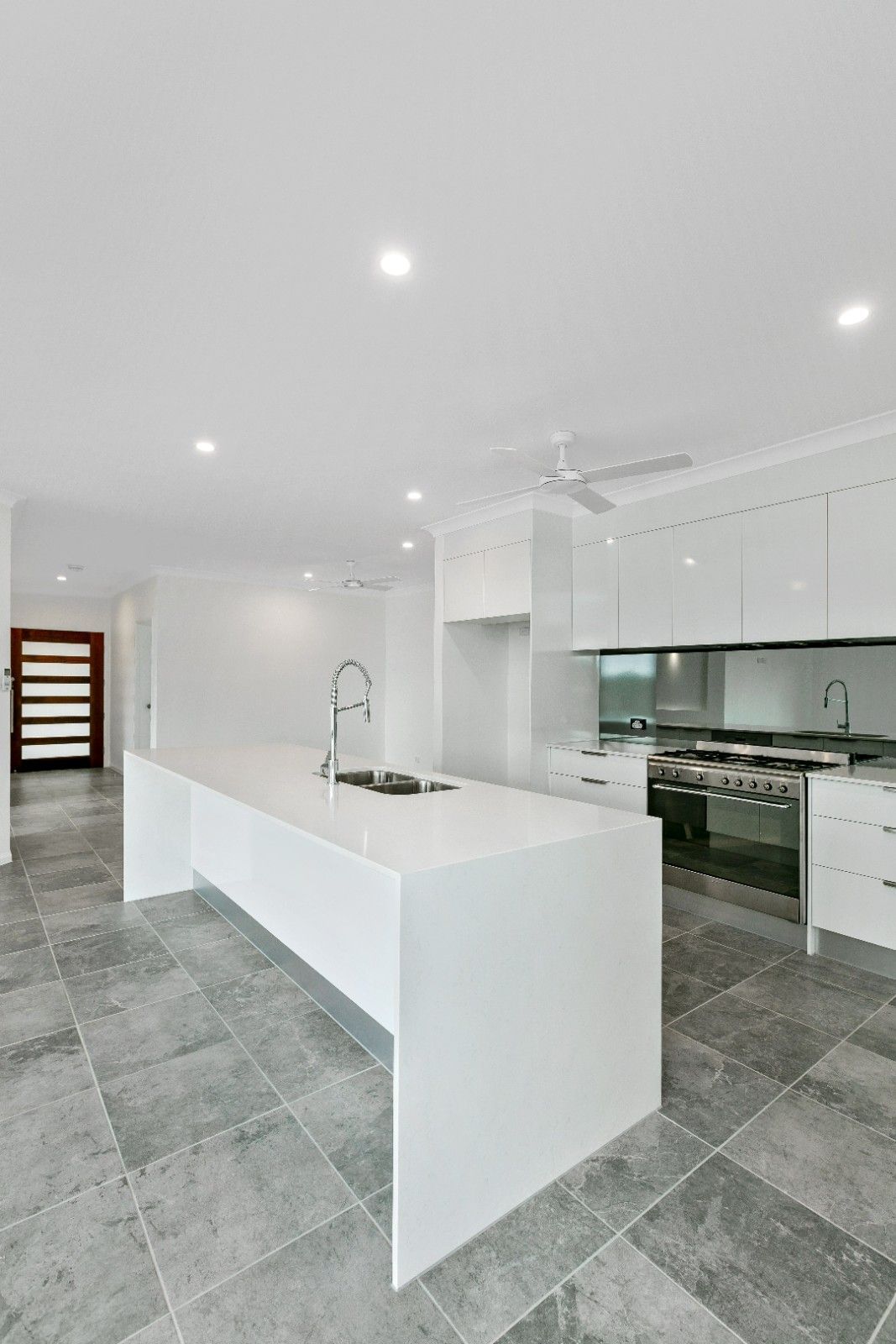 A Kitchen With White Cabinets and a Large Island — Ashlee Jones Homes in Gordonvale, QLD