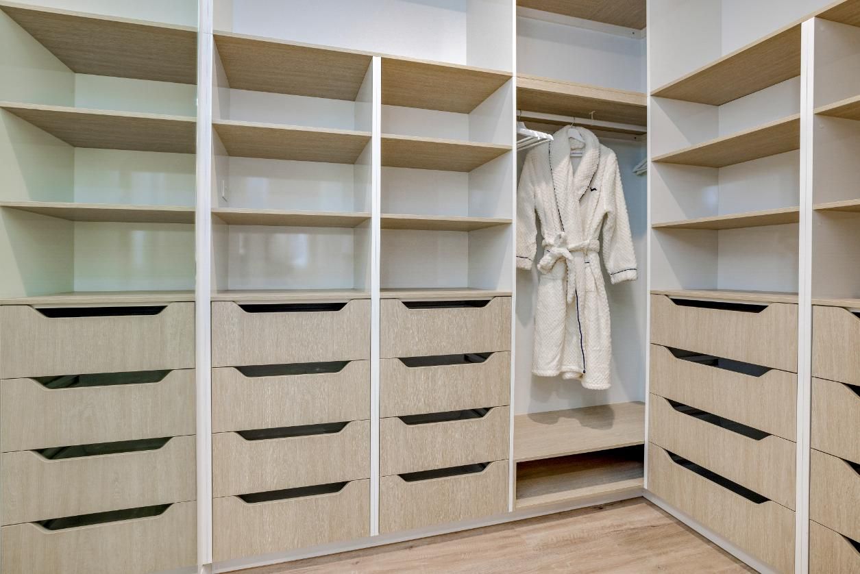 A Walk in Closet With Lots of Shelves and Drawers and a Robe Hanging on the Wall — Ashlee Jones Homes in Gordonvale, QLD