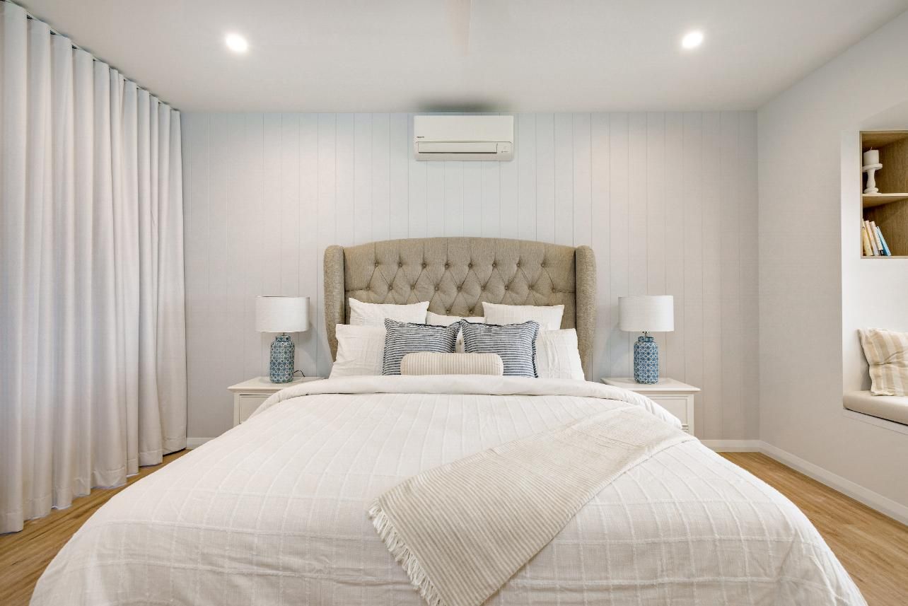 A Bedroom With a Bed , Two Nightstands , and a Window Seat — Ashlee Jones Homes in Gordonvale, QLD