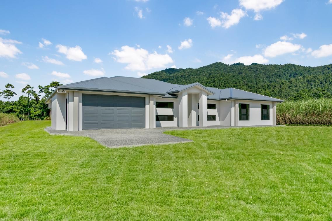 A Large House is Sitting on Top of a Lush Green Field — Ashlee Jones Homes in Gordonvale, QLD