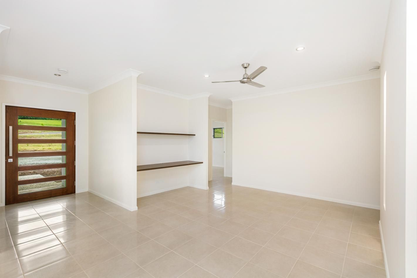 An Empty Living Room With a Ceiling Fan and a Door — Ashlee Jones Homes in Gordonvale, QLD