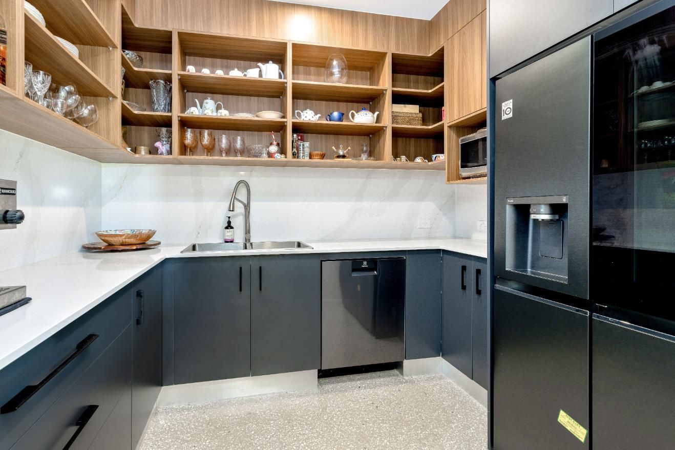 A Kitchen With Black Cabinets, Stainless Steel Appliances, a Sink, and a Refrigerator — Ashlee Jones Homes in Gordonvale, QLD