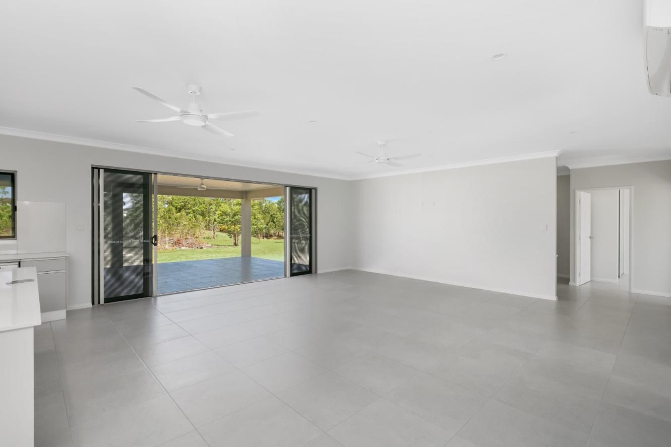 An Empty Living Room With Sliding Glass Doors and a Ceiling Fan — Ashlee Jones Homes in Gordonvale, QLD
