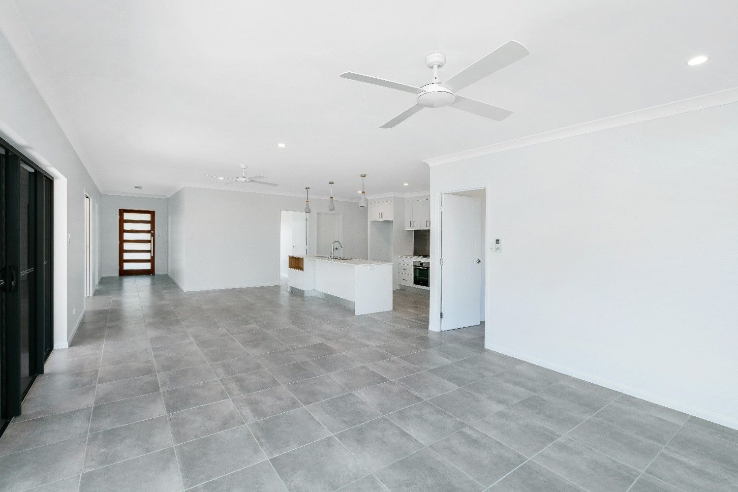 An Empty Living Room With a Ceiling Fan and a Tiled Floor — Ashlee Jones Homes in Gordonvale, QLD