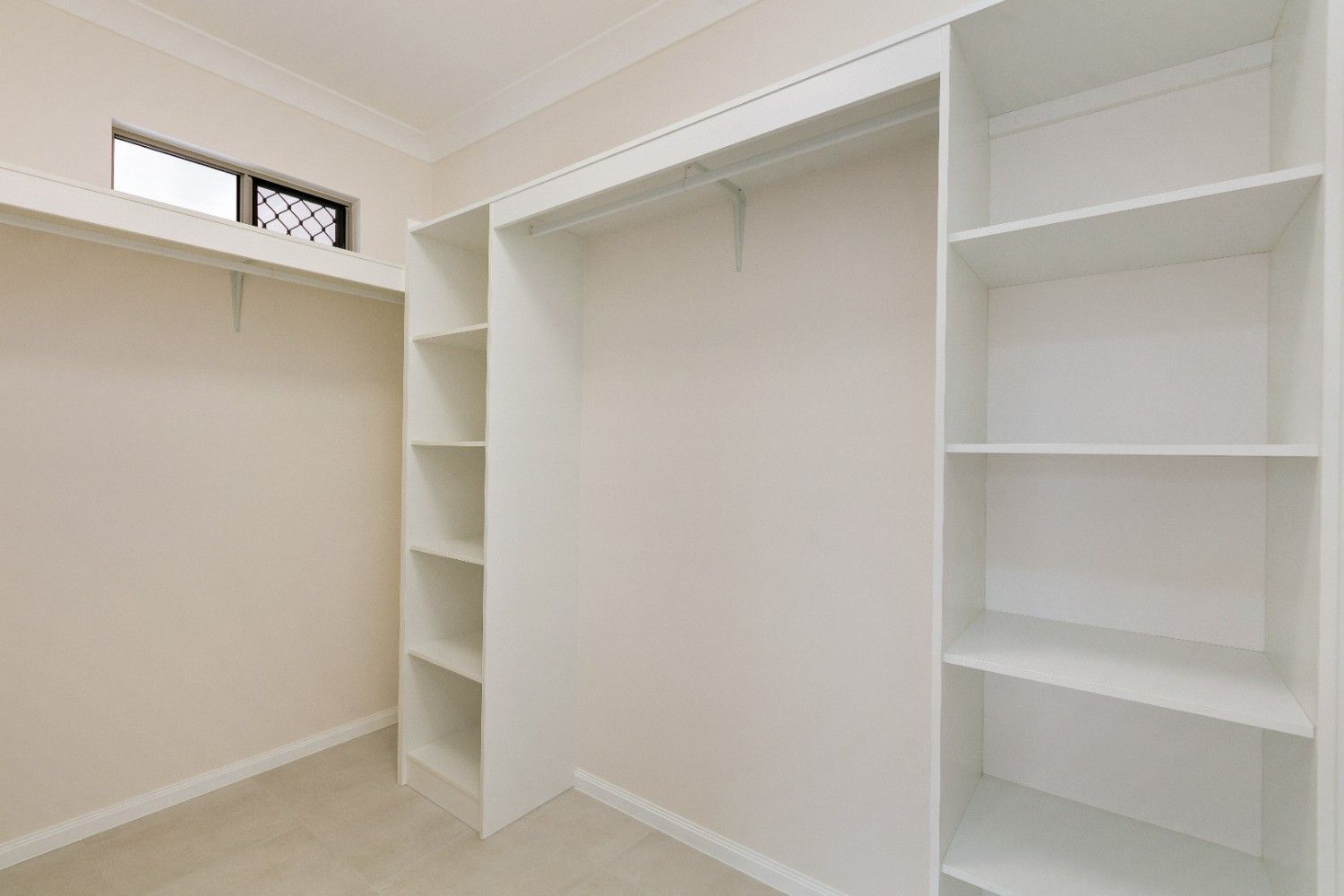 An Empty Walk in Closet With White Shelves and a Window — Ashlee Jones Homes in Gordonvale, QLD