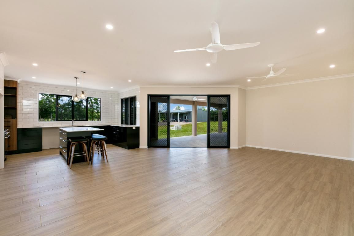 A Large Empty Room With Hardwood Floors and a Ceiling Fan — Ashlee Jones Homes in Gordonvale, QLD