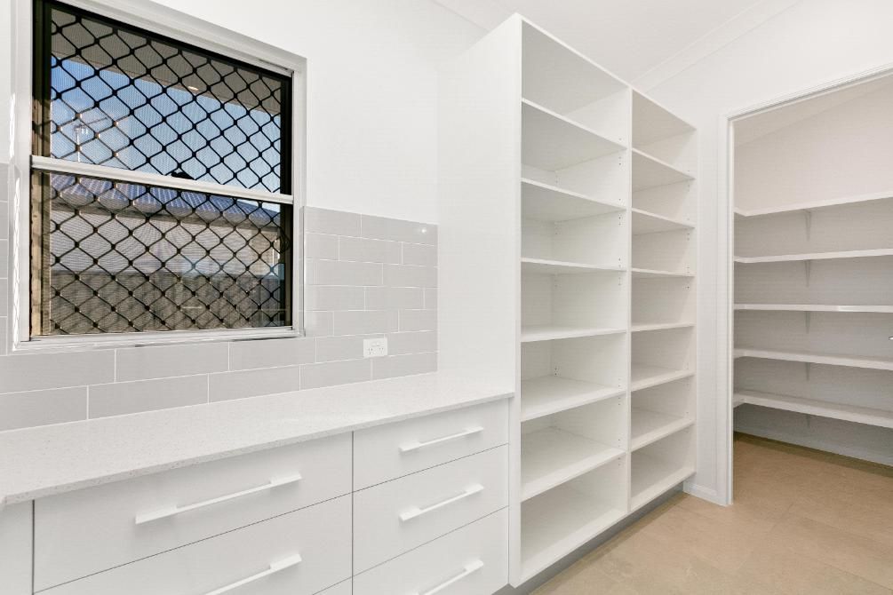 A Kitchen With White Cabinets and Shelves and a Window — Ashlee Jones Homes in Gordonvale, QLD