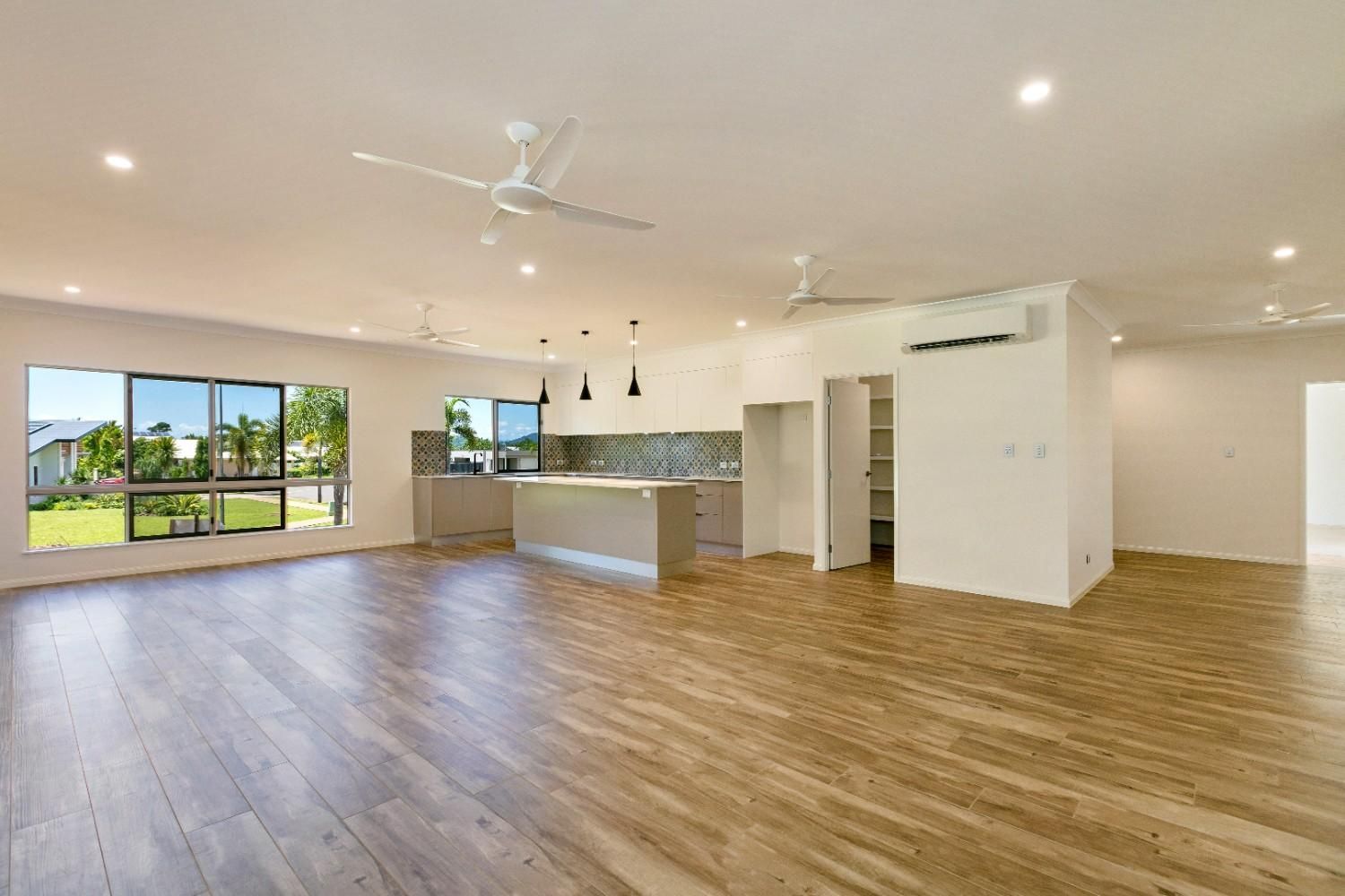 A Large Empty Room With Hardwood Floors and a Ceiling Fan — Ashlee Jones Homes in Gordonvale, QLD