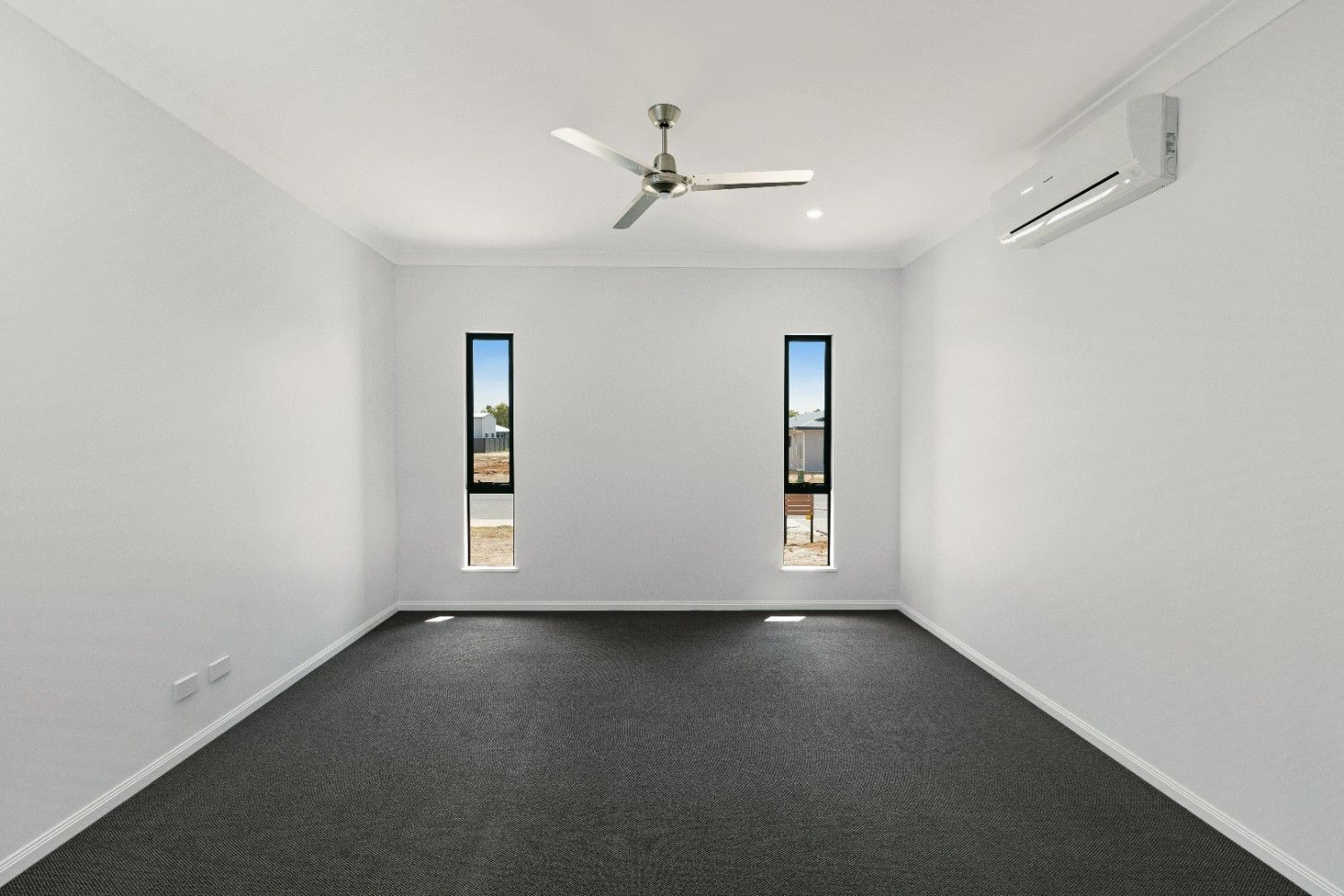 An Empty Room With a Ceiling Fan and Two Windows — Ashlee Jones Homes in Gordonvale, QLD