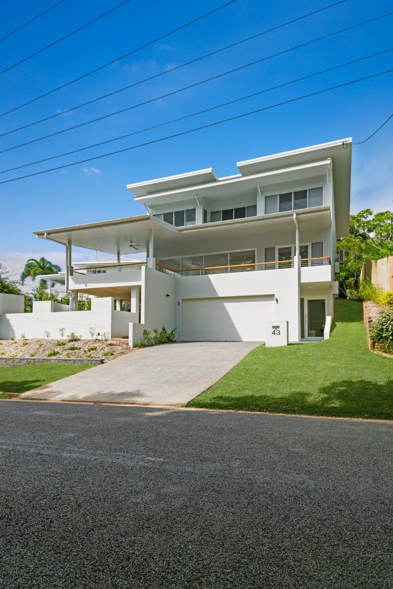 A Large White House is Sitting on Top of a Lush Green Hill — Ashlee Jones Homes in Gordonvale, QLD