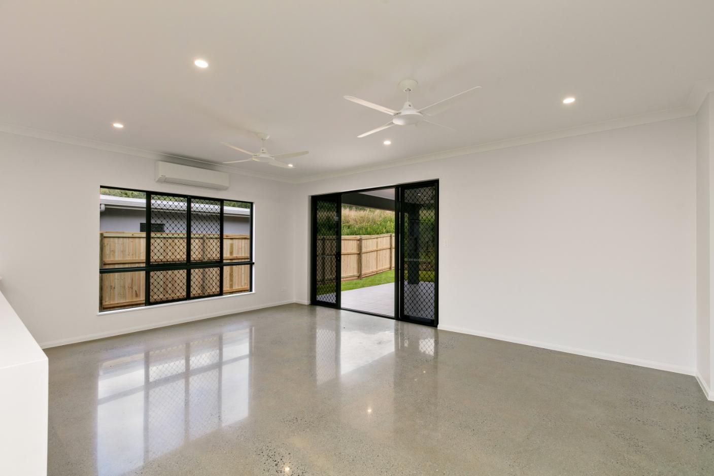 An Empty Living Room With a Ceiling Fan and Sliding Glass Doors — Ashlee Jones Homes in Gordonvale, QLD