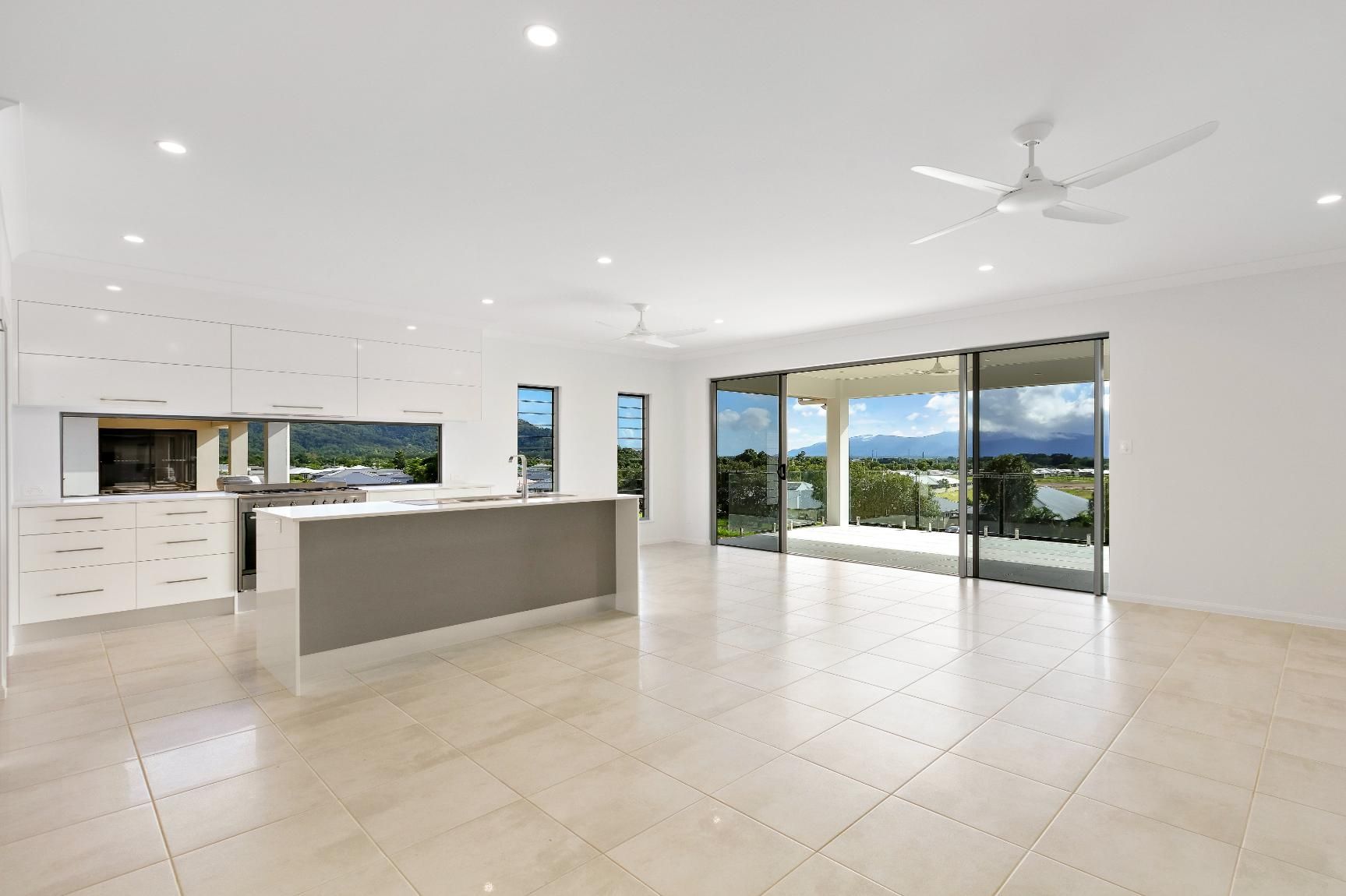 An Empty Kitchen With a Ceiling Fan and Sliding Glass Doors — Ashlee Jones Homes in Gordonvale, QLD