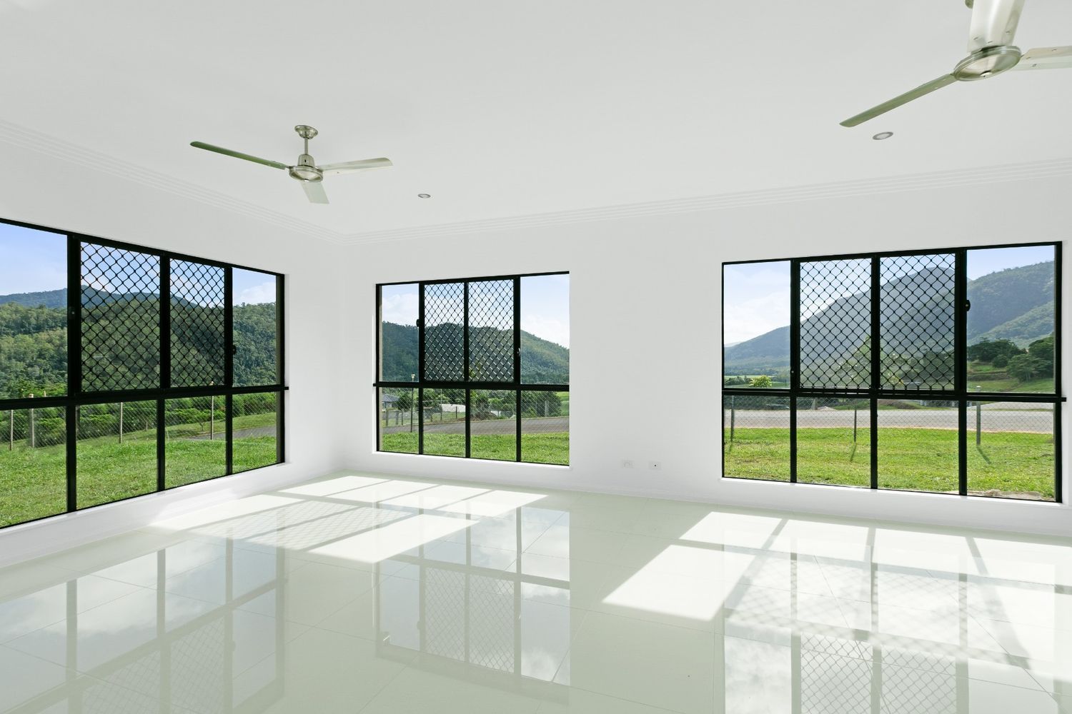 An Empty Room With a Windows and a Ceiling Fan — Ashlee Jones Homes in Gordonvale, QLD