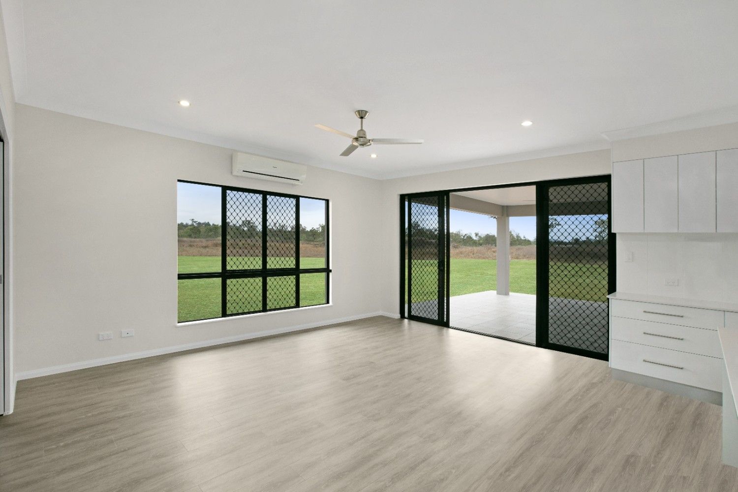 An Empty Living Room With Sliding Glass Doors and a Ceiling Fan — Ashlee Jones Homes in Gordonvale, QLD