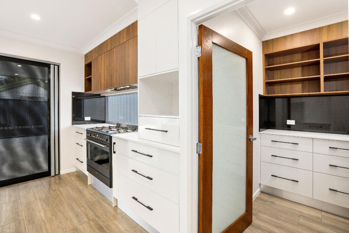 A Kitchen With White Cabinets, a Stove, a Refrigerator, and a Glass Door — Ashlee Jones Homes in Gordonvale, QLD