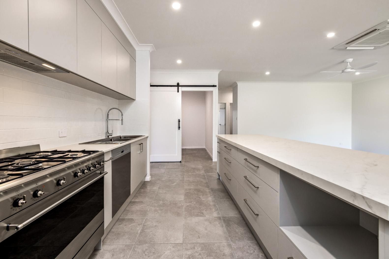 A Kitchen With a Stove, Sink , and Sliding Barn Door — Ashlee Jones Homes in Gordonvale, QLD