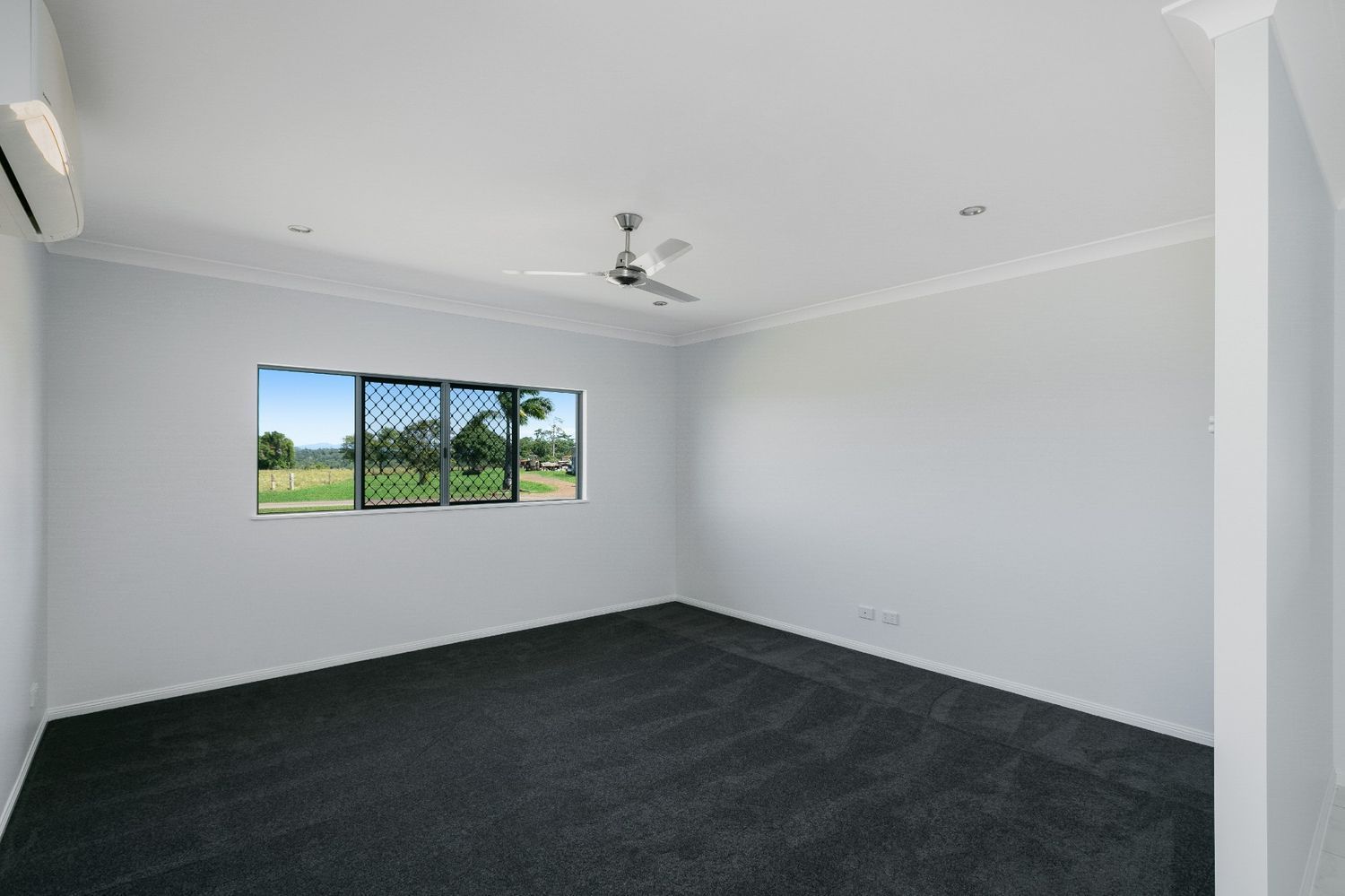 An Empty Room With a Ceiling Fan and Three Windows — Ashlee Jones Homes in Gordonvale, QLD