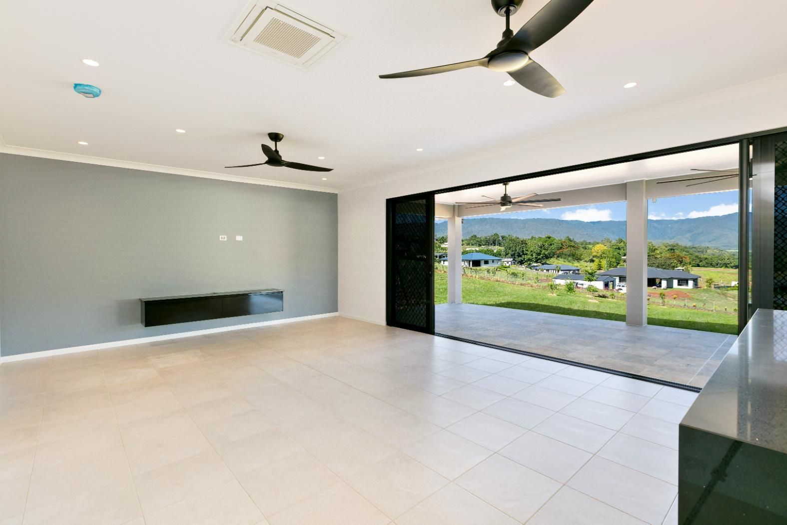 An Empty Living Room With a Ceiling Fan and a Sliding Glass Door — Ashlee Jones Homes in Gordonvale, QLD