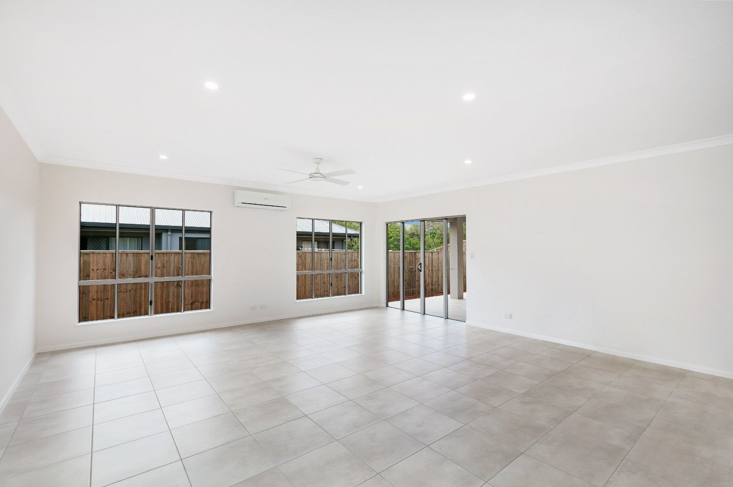An Empty Living Room With Tile Floors and a Ceiling Fan — Ashlee Jones Homes in Gordonvale, QLD