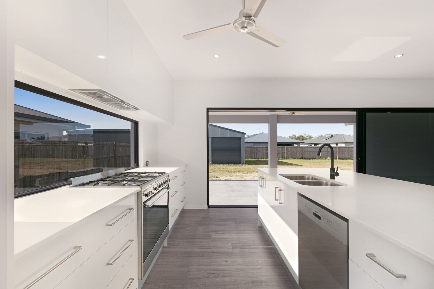 A Kitchen With White Cabinets and a Ceiling Fan — Ashlee Jones Homes in Gordonvale, QLD