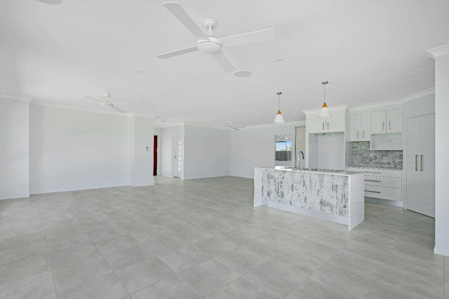 A Large Empty Room With a Ceiling Fan and a Kitchen — Ashlee Jones Homes in Gordonvale, QLD