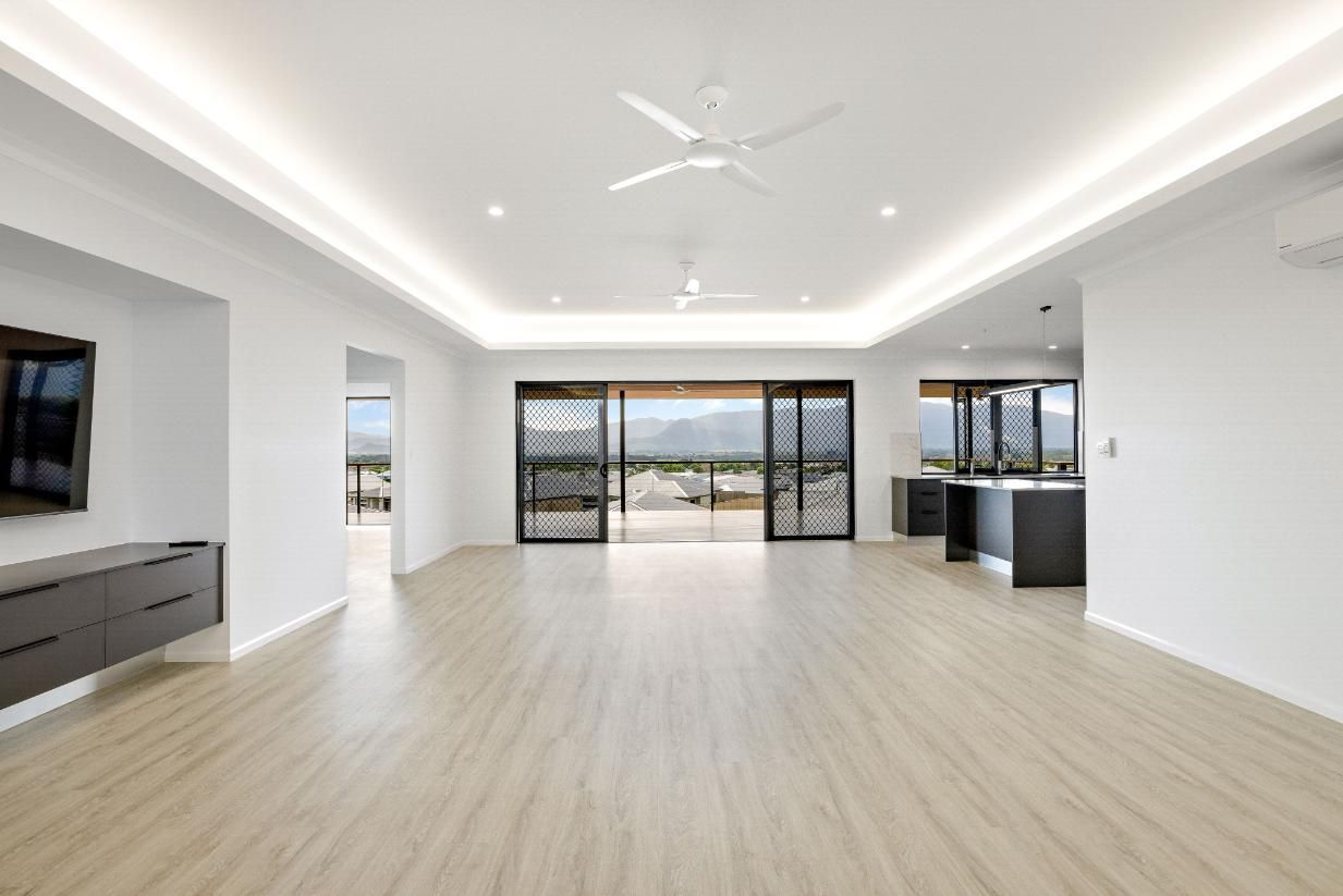 An Empty Living Room With a Ceiling Fan and a Flat Screen Tv — Ashlee Jones Homes in Gordonvale, QLD