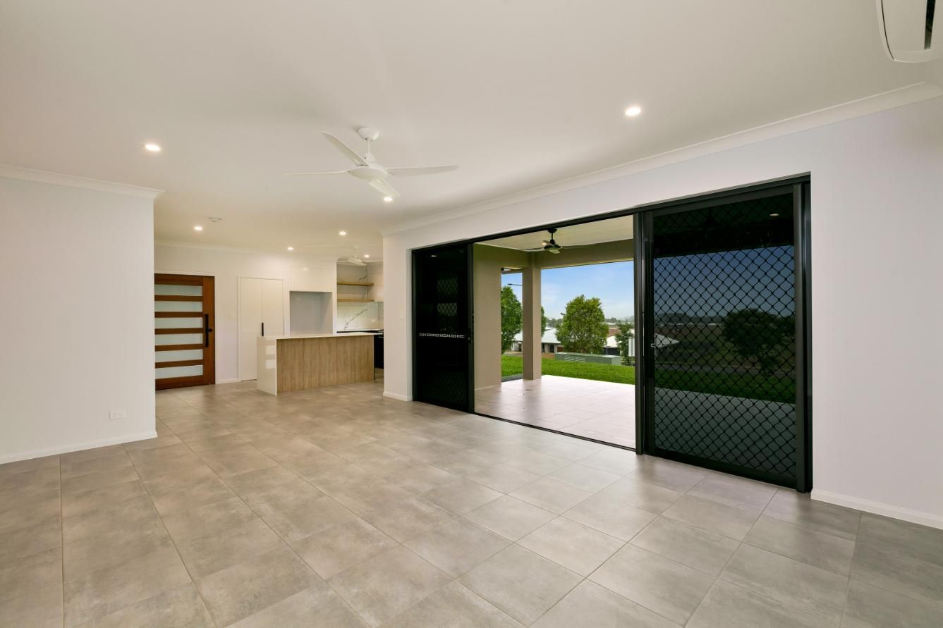 An Empty Living Room With Sliding Glass Doors Leading to a Patio — Ashlee Jones Homes in Gordonvale, QLD