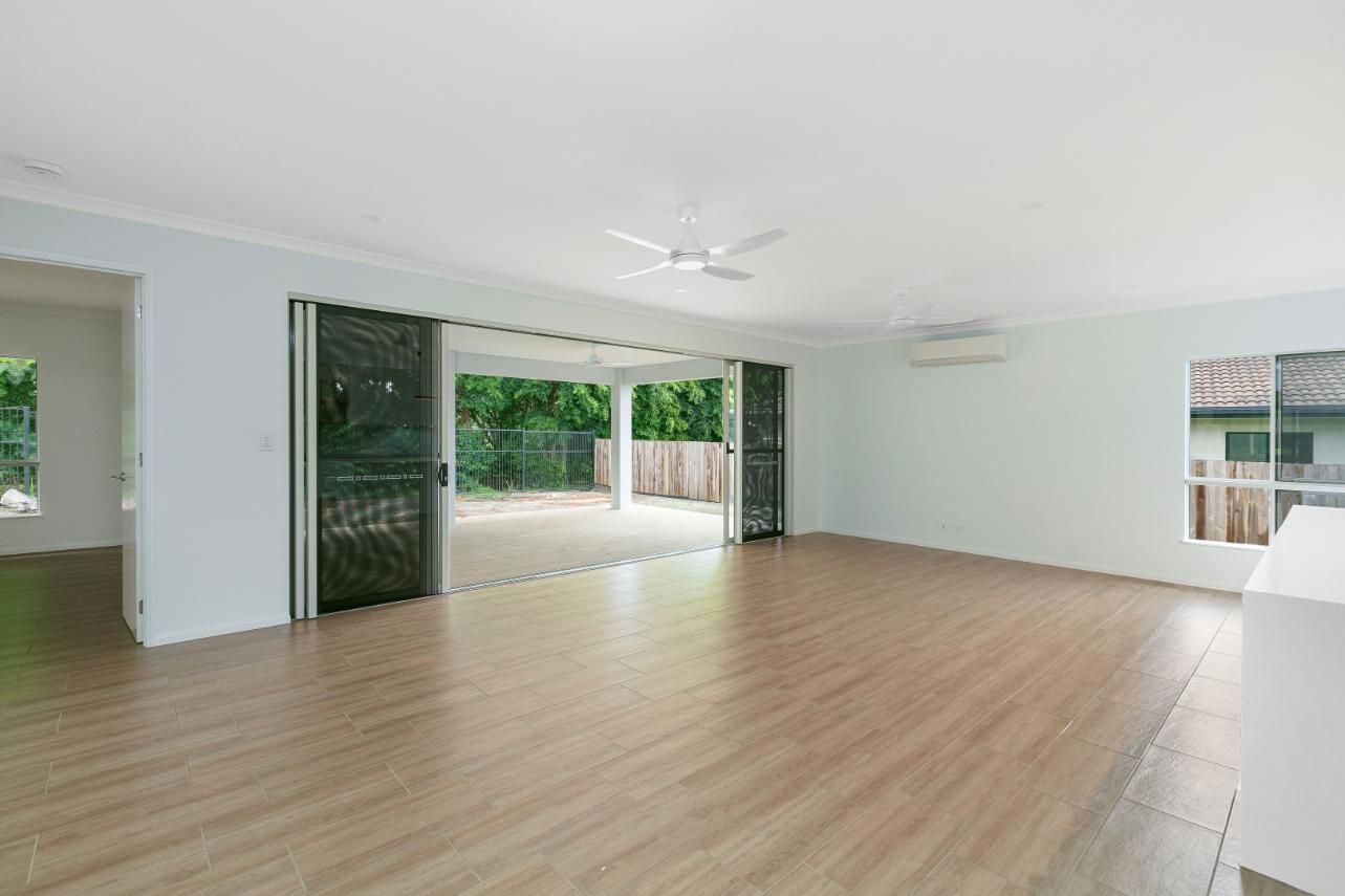 An Empty Living Room With Hardwood Floors and a Ceiling Fan — Ashlee Jones Homes in Gordonvale, QLD