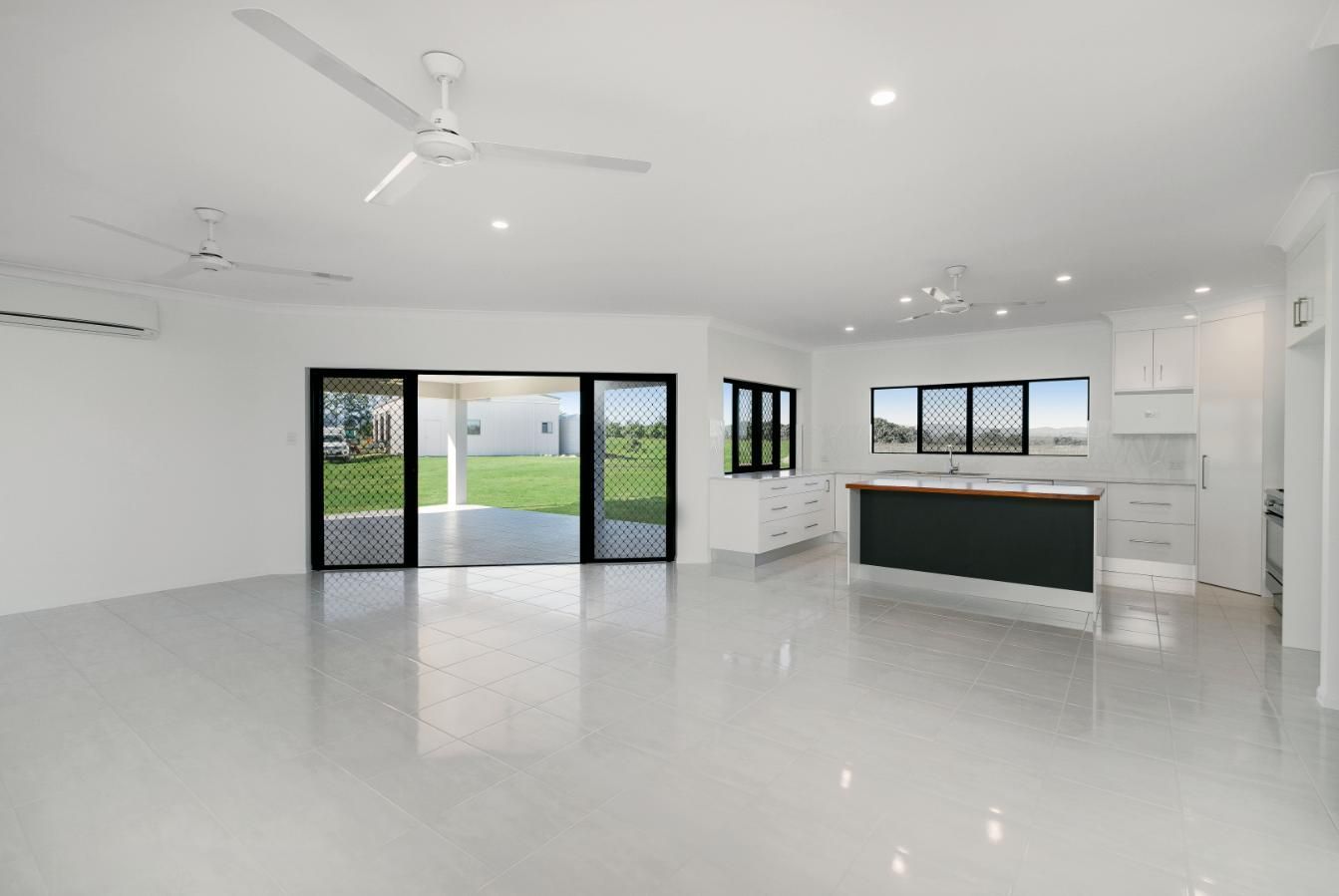 An Empty Living Room With a Ceiling Fan and Sliding Glass Doors Leading to a Kitchen — Ashlee Jones Homes in Gordonvale, QLD