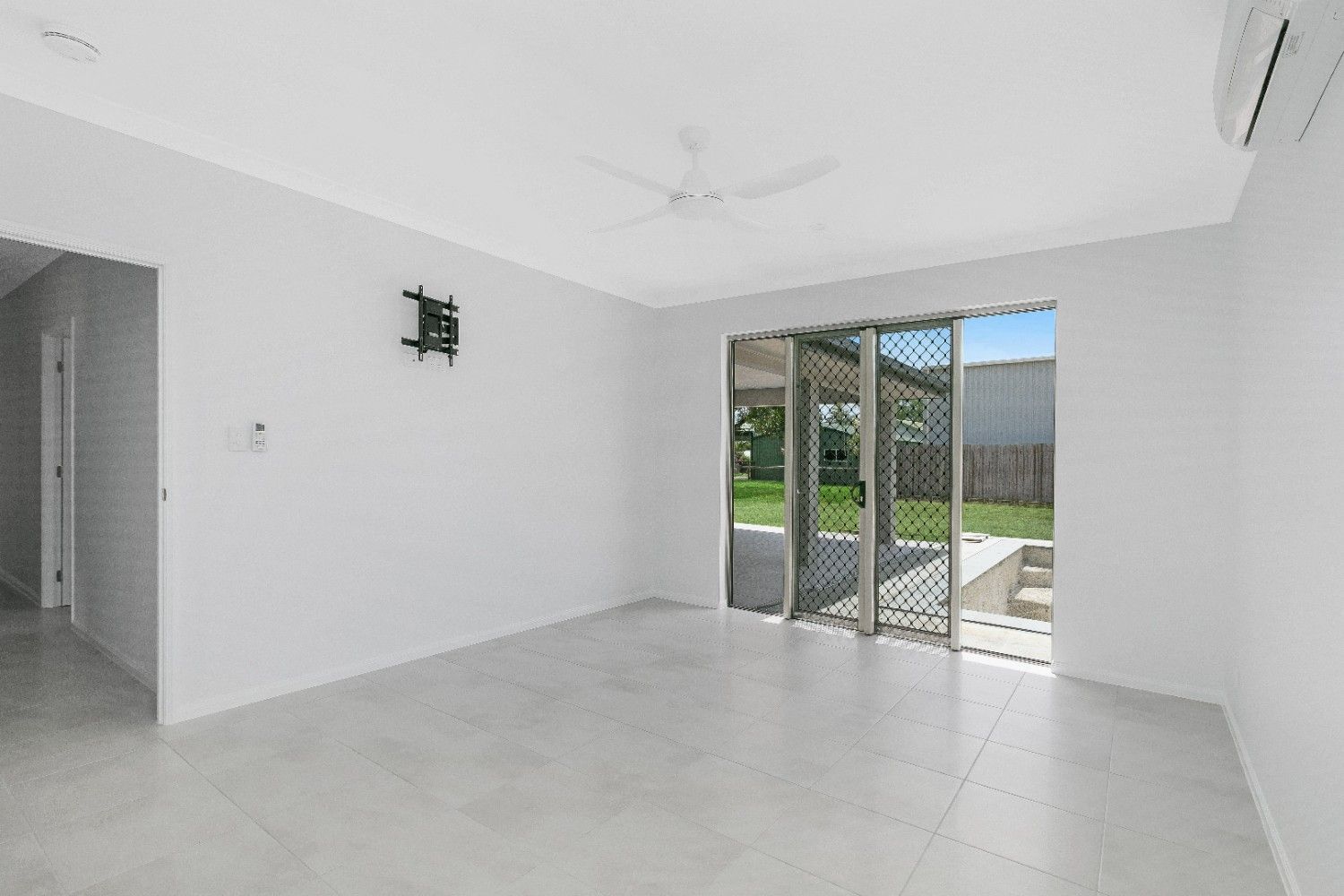 An Empty Living Room With Sliding Glass Doors and a Ceiling Fan — Ashlee Jones Homes in Gordonvale, QLD